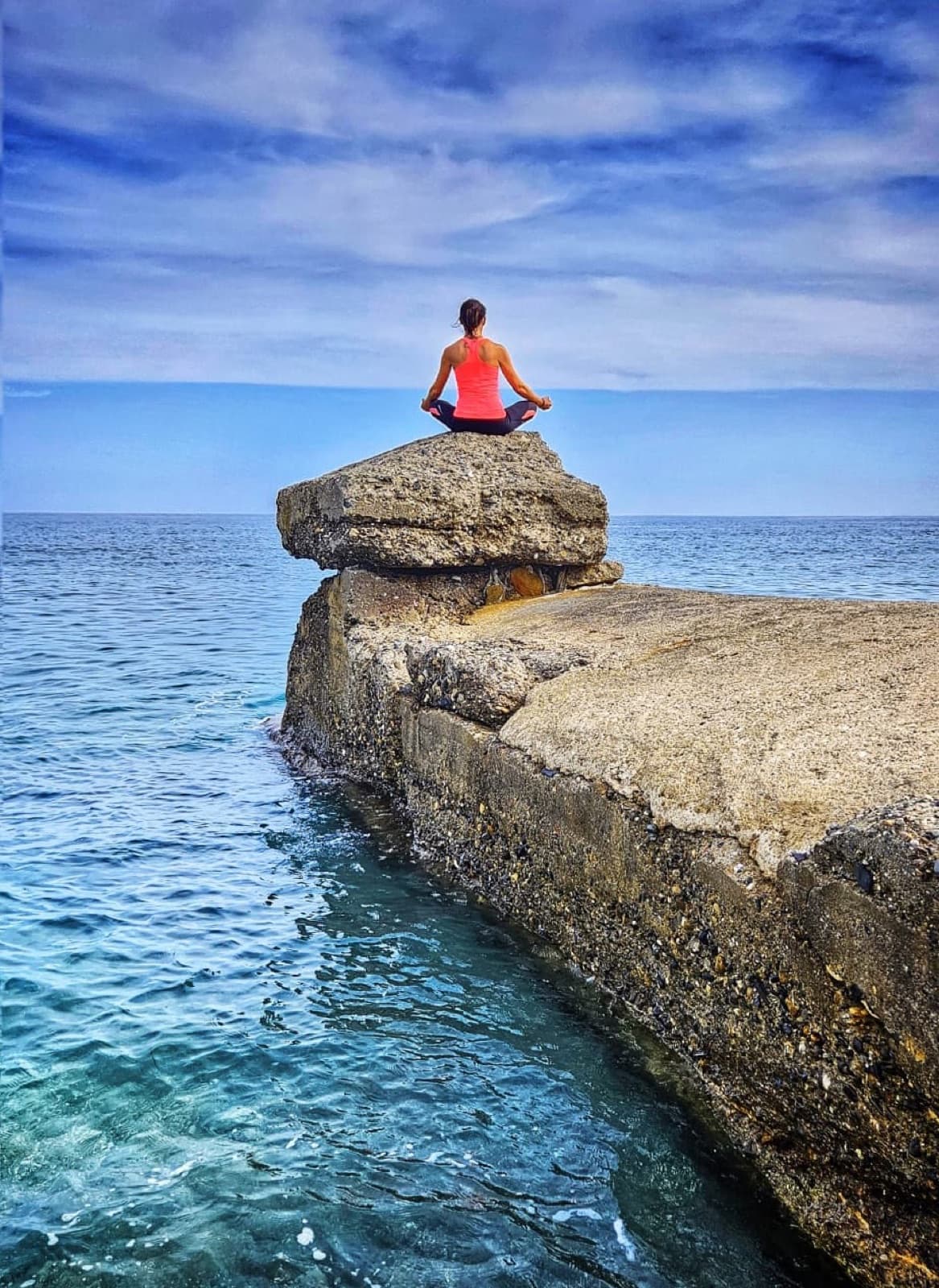 Eva meditating on a rock above the sea in Gibraltar