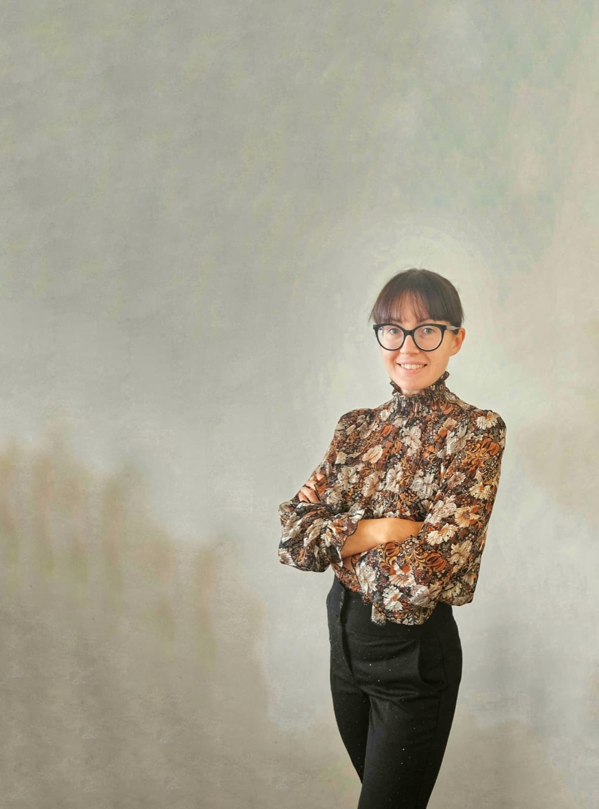 Eva standing against a textured grey wall
